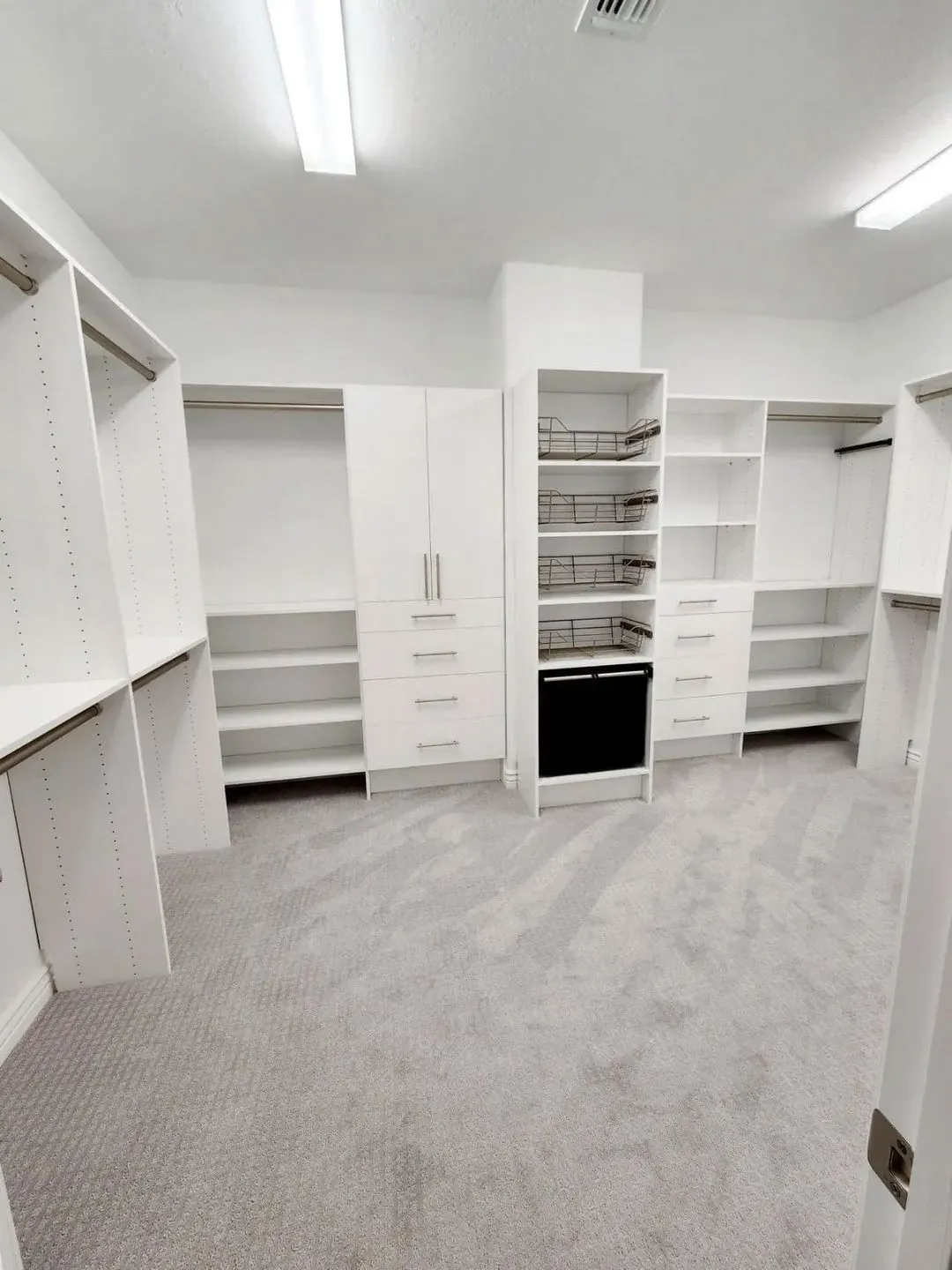 Spacious bright white custom master walk-in closet with built-in shelving and soft grey carpet in a Pinellas County, FL home